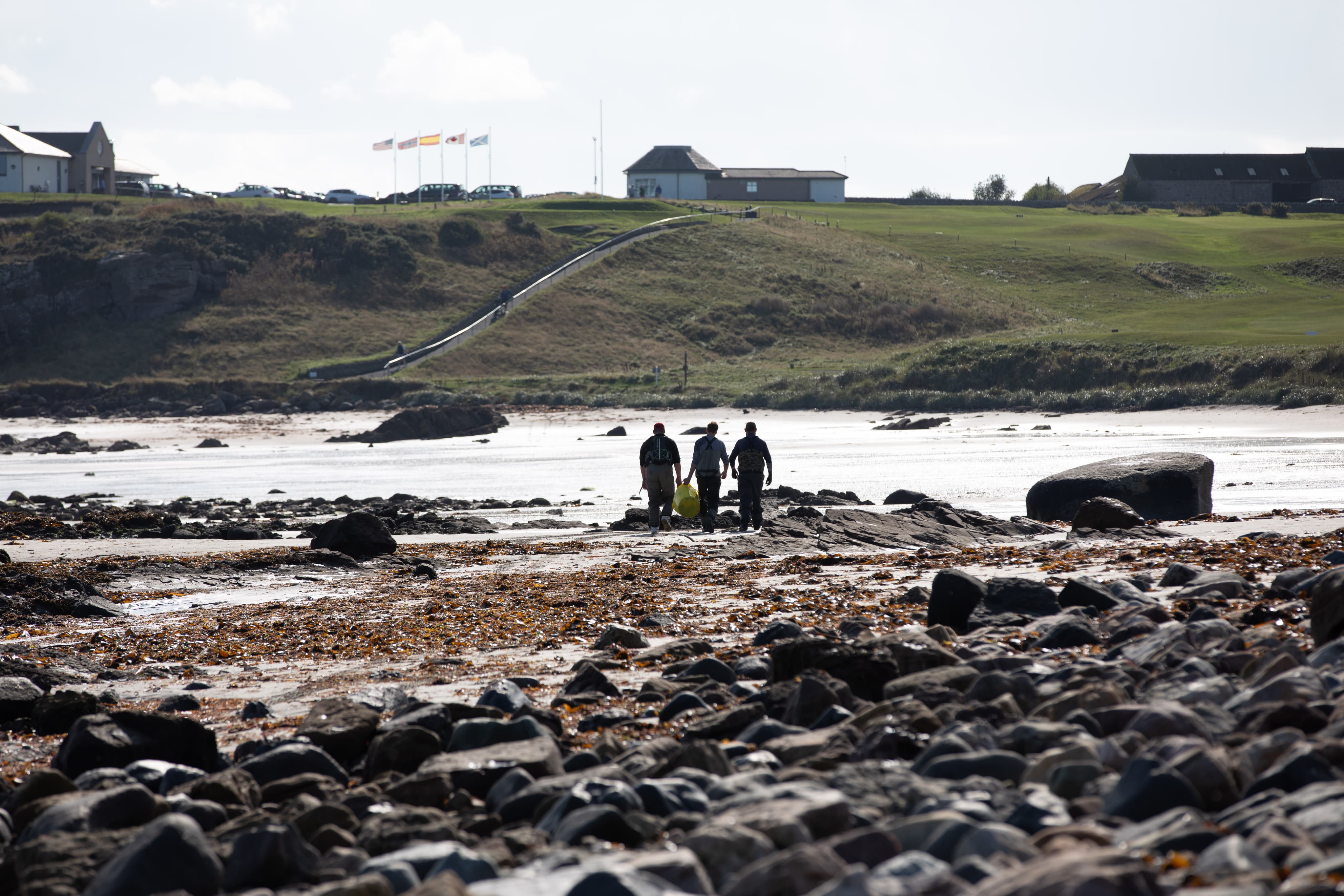 people walking across river bed when tide is out